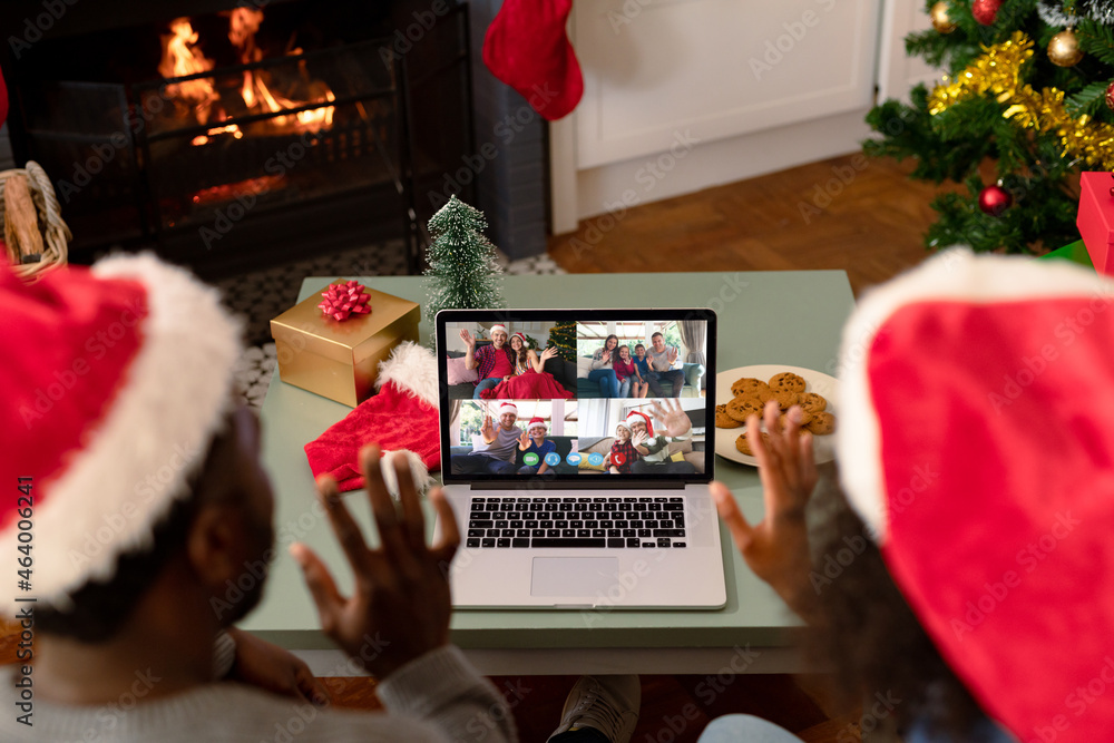 一对戴着圣诞老人帽的非裔美国夫妇在圣诞笔记本电脑上与朋友视频通话
