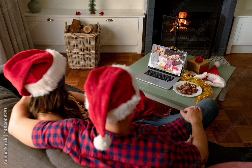 戴着圣诞老人帽的白人夫妇在圣诞笔记本电脑上与朋友视频通话