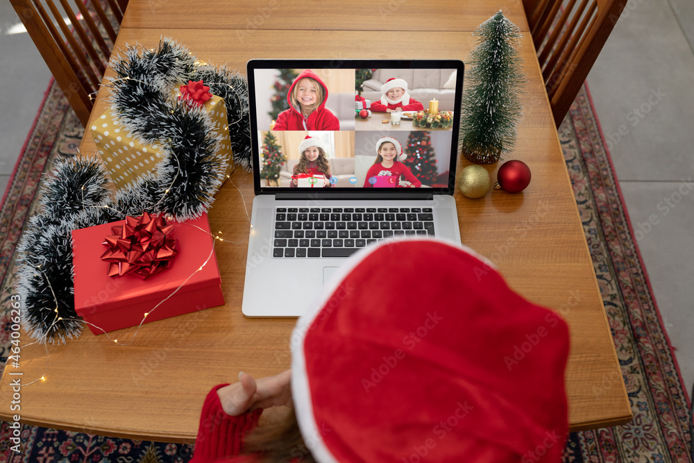 戴圣诞老人帽的白人妇女在圣诞笔记本电脑上与朋友视频通话