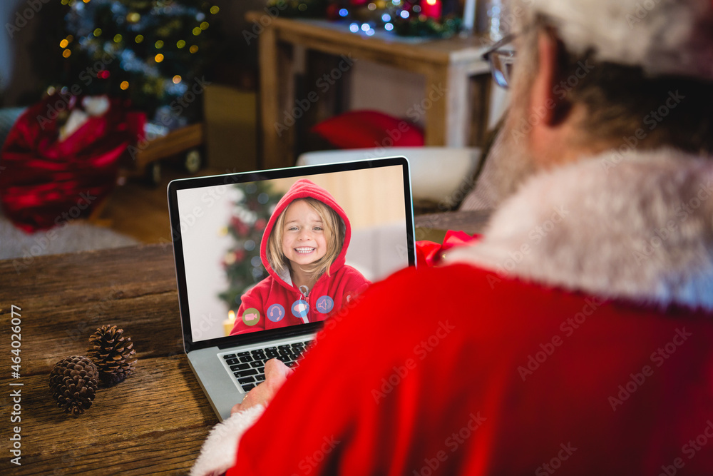 圣诞老人与微笑的高加索女孩进行笔记本电脑圣诞视频通话