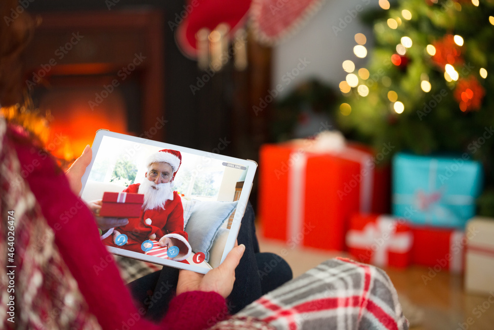 高加索女子与穿着圣诞老人服装的老年男子进行平板电脑圣诞视频通话