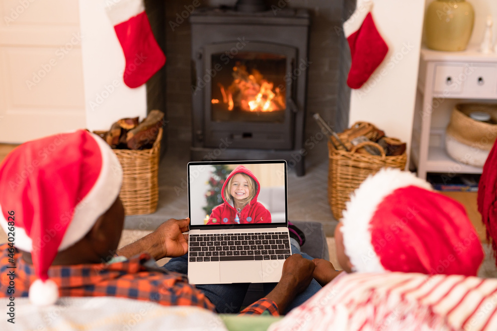 一对非洲裔美国夫妇与微笑的高加索女孩进行笔记本电脑圣诞视频通话