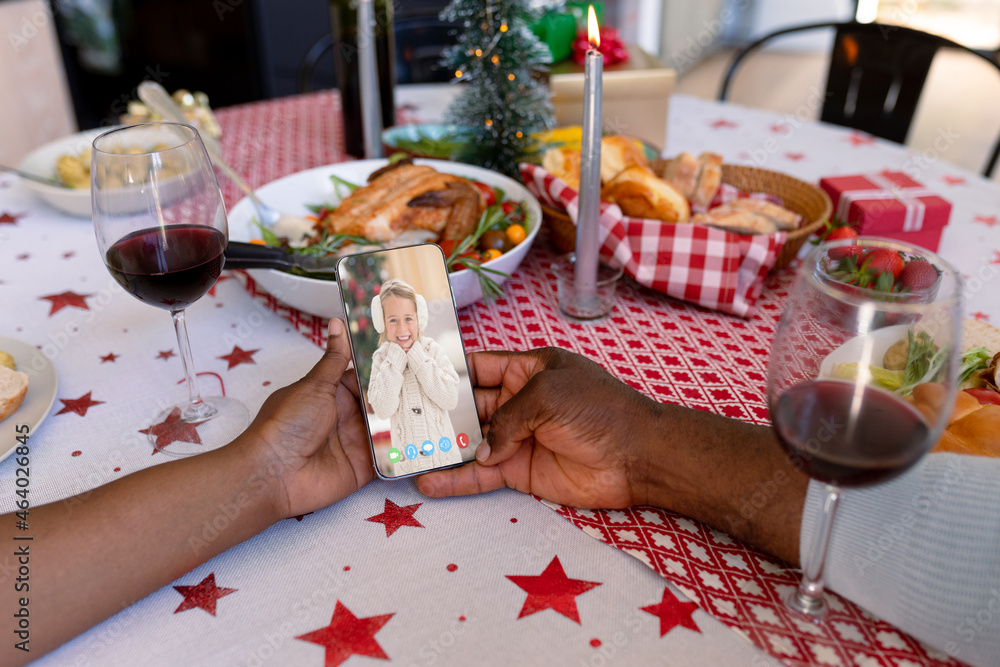 African american couple making smartphone christmas video call with smiling caucasian girl
