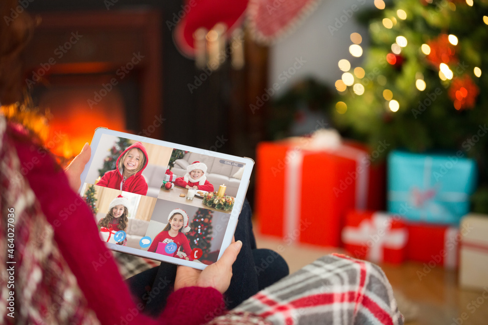 高加索妇女在圣诞平板电脑上与高加索儿童群视频通话