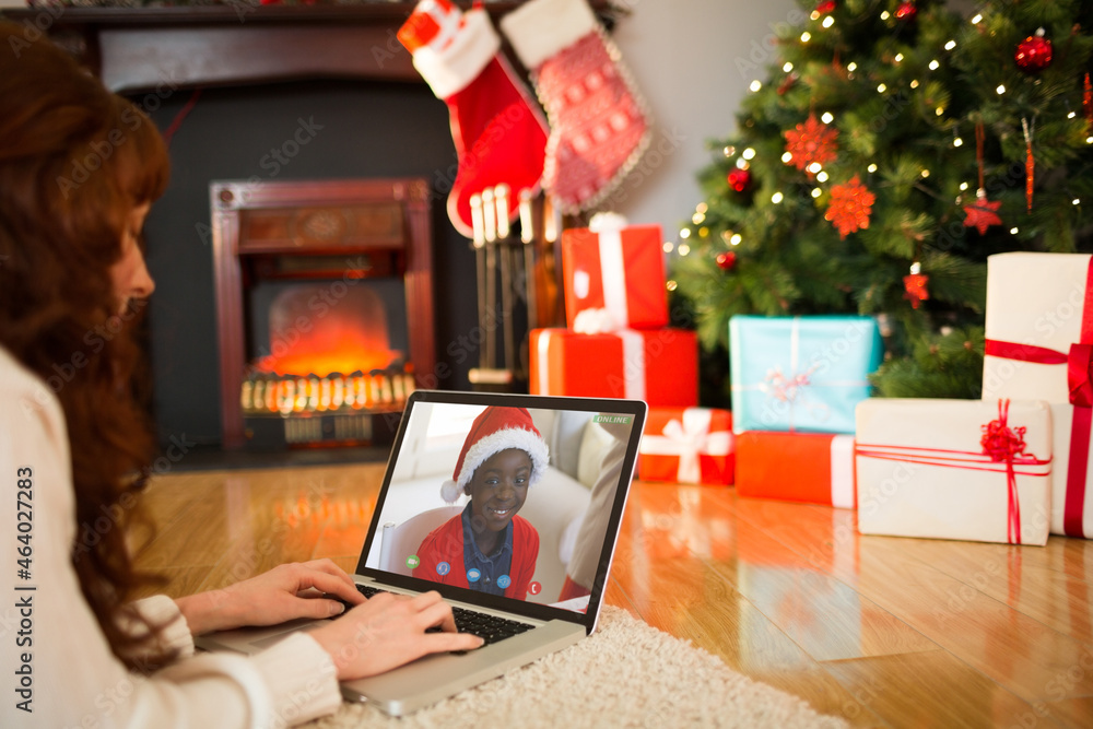 Caucasian woman on christmas laptop video call with african american boy