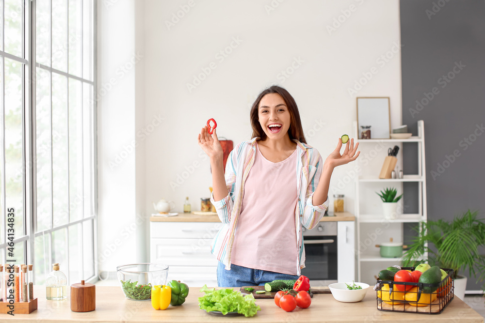 Young woman eating fresh vegetables in kitchen