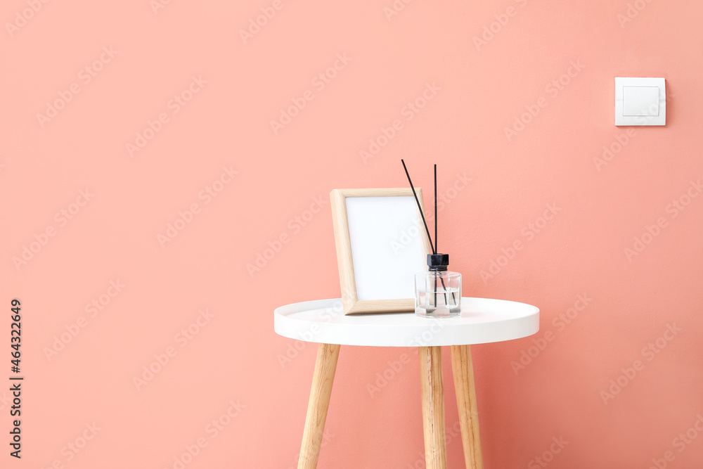 粉红色墙壁附近带框架和簧片扩散器的桌子