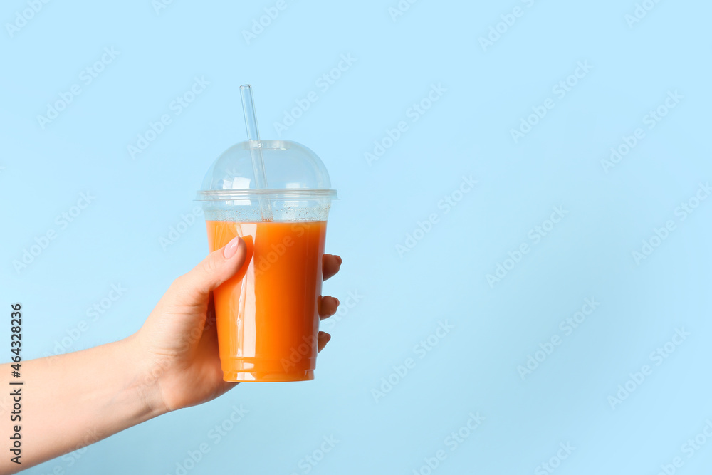 彩色背景上有健康果汁塑料杯的女性手