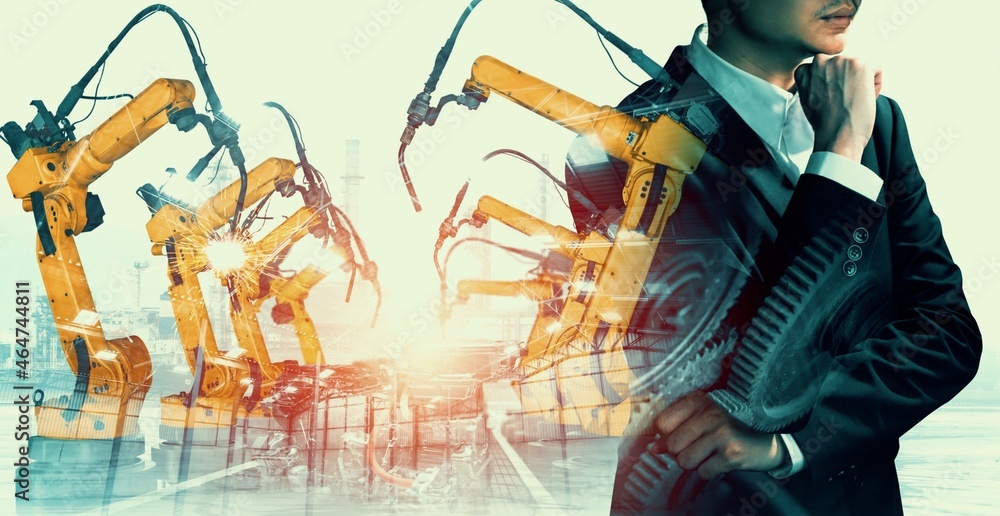 机械化工业机械臂和工厂工人的双重曝光。机器人技术的概念