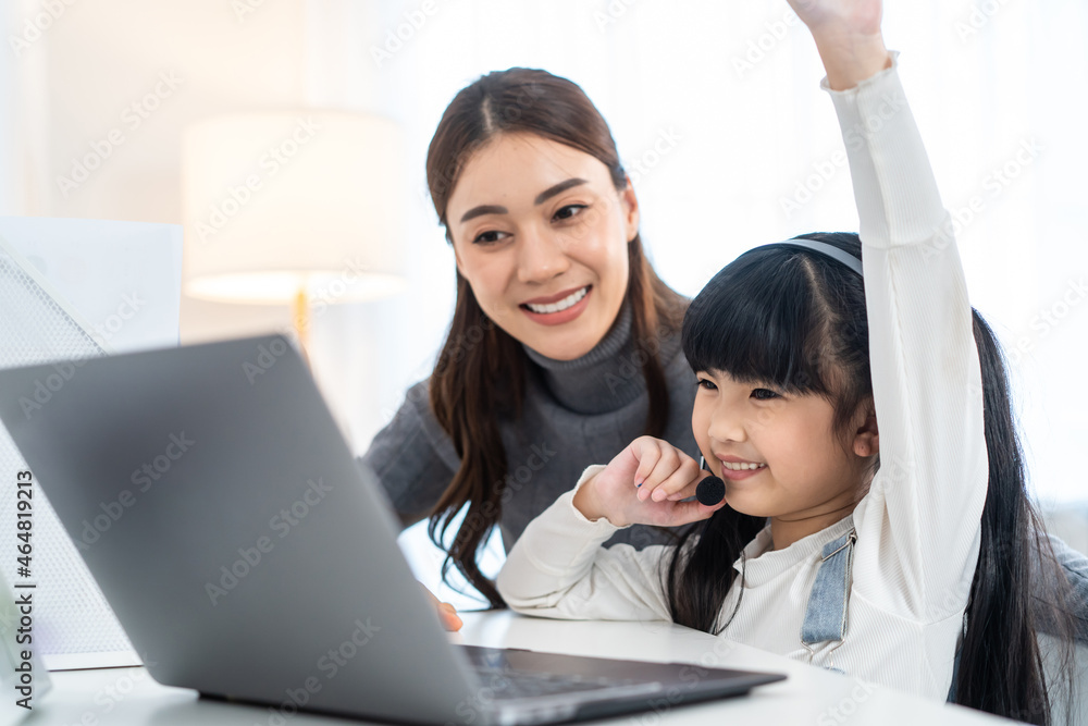 亚洲小女孩在家和妈妈一起学习网课。