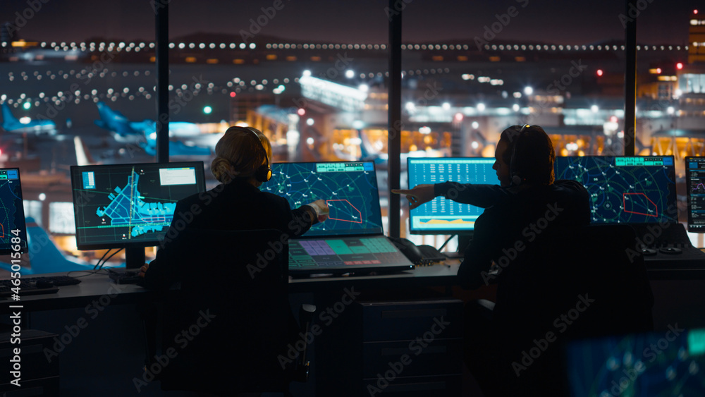 夜间在现代化机场塔台工作的多元化空中交通管制团队。办公室里到处都是