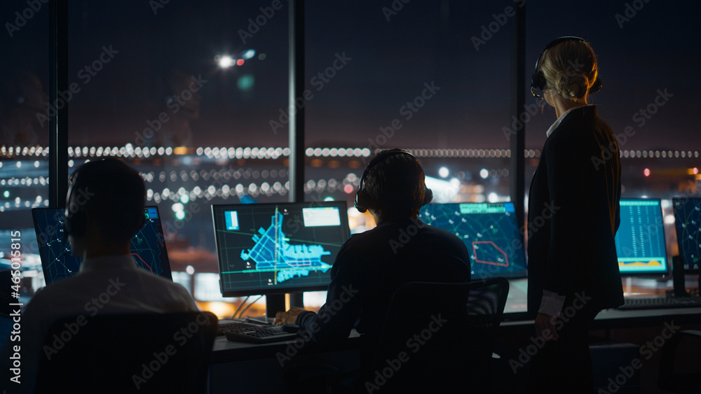 Female and Male Air Traffic Controllers with Headsets Talk in Airport Tower at Night. Office Room Fu