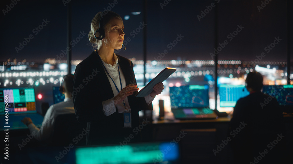 在机场大楼的平板电脑上工作的白人女空中交通管制员。办公室里满是D