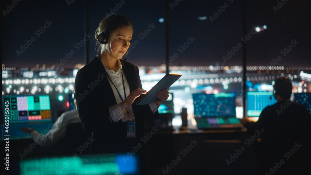高加索女空中交通管制员在机场塔台的平板电脑上工作。办公室里满是D