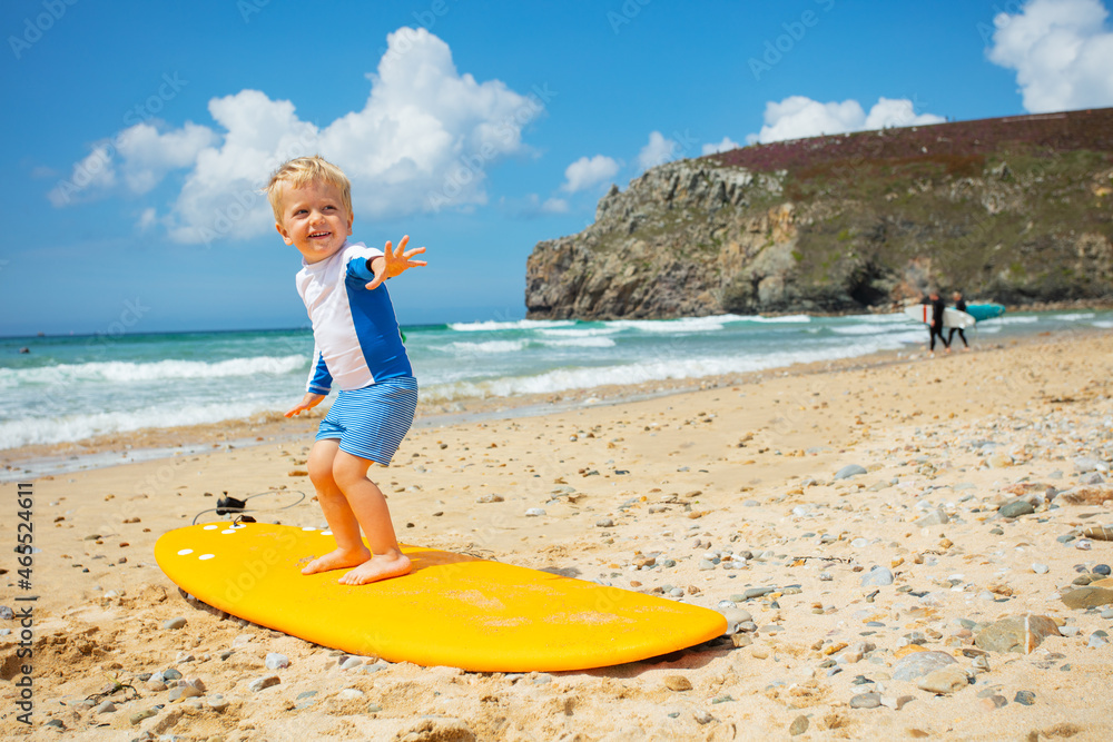 可爱的金发幼童练习冲浪板姿势