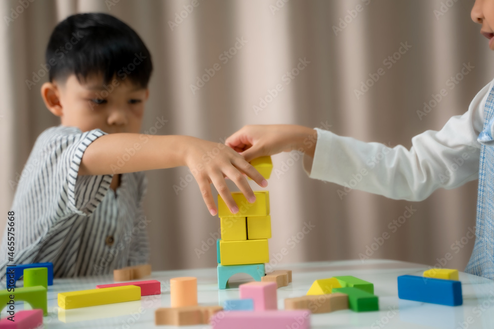 快乐的孩子在玩五颜六色的玩具积木，孩子们坐在防洪堤上建造积木玩具塔