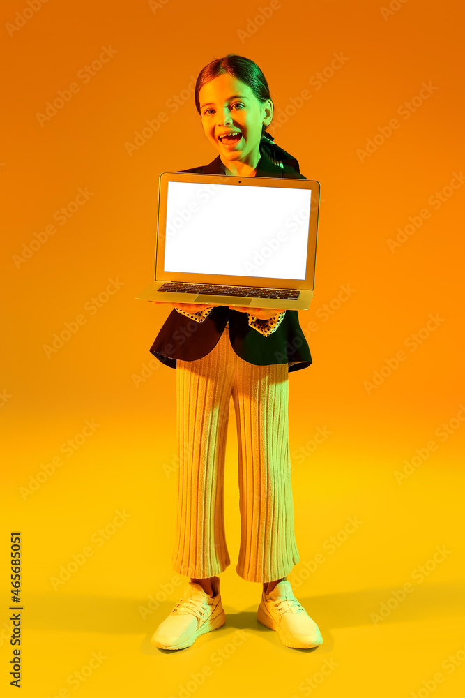 黄色背景笔记本电脑的小女孩。黑色星期五大减价