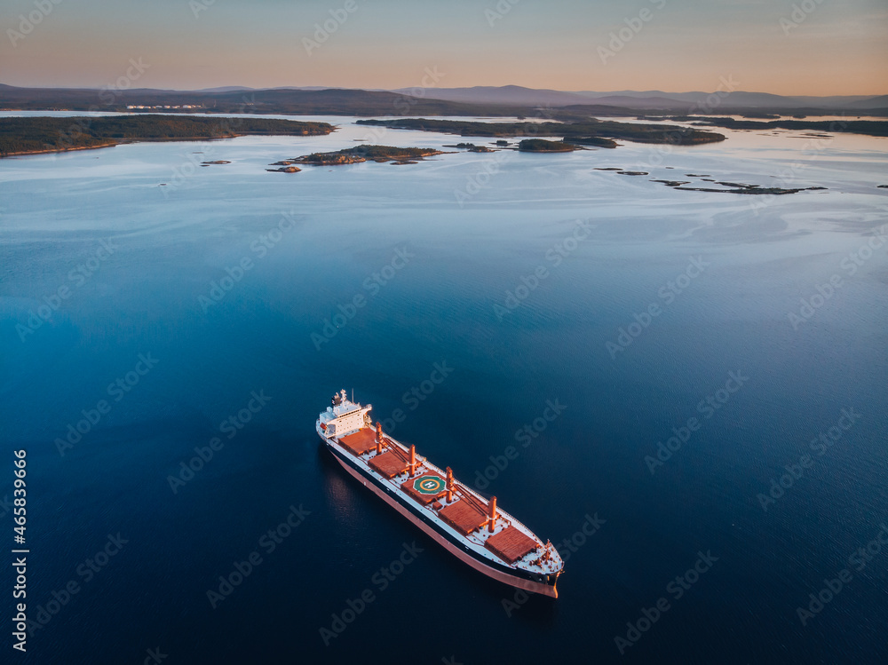 Cargo Ship docked at open sea close to harbour. Drone aerial bird eye view