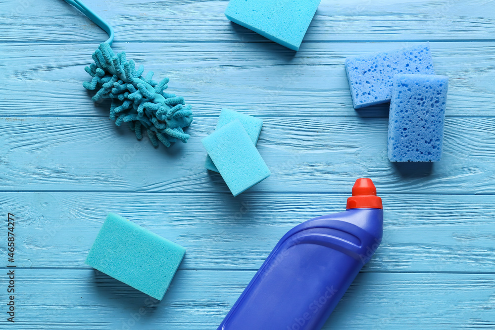 蓝色清洁海绵和彩色木质背景的清洁剂瓶