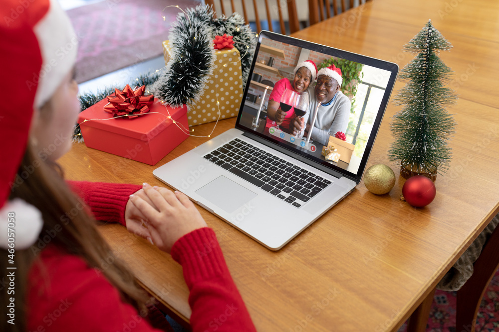 戴着圣诞老人帽的白人妇女与一对微笑的非裔美国夫妇进行圣诞笔记本电脑视频通话