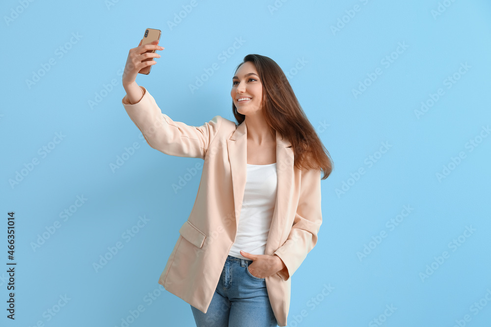 Beautiful smiling woman taking selfie on color background