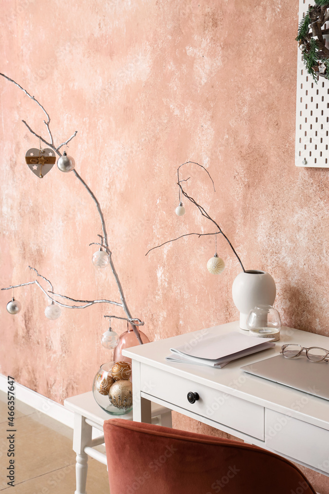 粉红色墙壁附近桌子上花瓶里有圣诞球的树枝