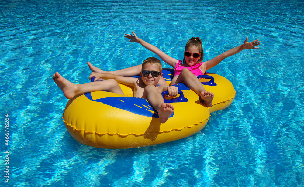 在室外游泳池里，男孩和女孩在充气浮漂上。