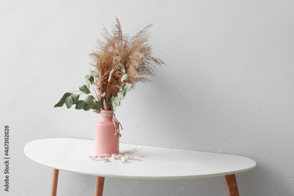 灯墙附近桌上放着漂亮的干花花束的花瓶
