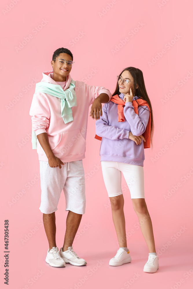 时尚的年轻情侣穿着粉色背景的连帽衫