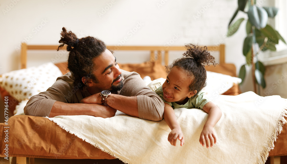快乐的非裔美国人家庭父子小男孩躺在床上放松