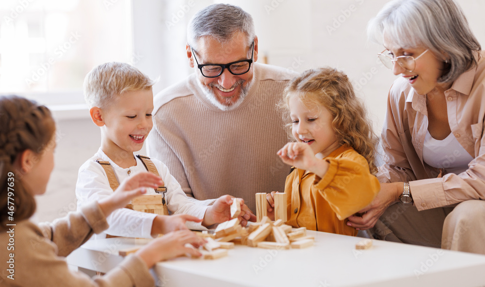 兴奋的孩子们坐在沙发上，在家里和积极的老爷爷奶奶玩游戏詹加
