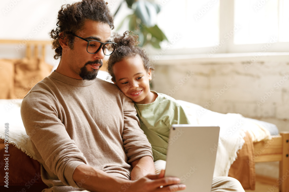Happy african american family little son with dad watching funny videos on tablet together at home