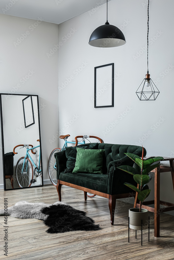 带绿色沙发、镜子和自行车的浅色客厅内部