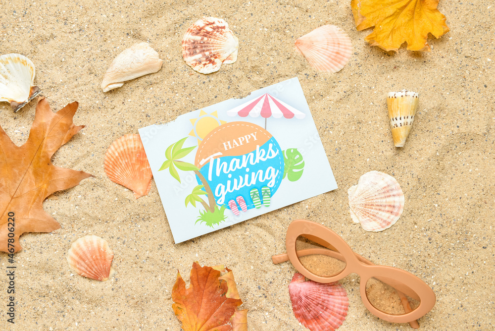 干树叶、贝壳、太阳镜和纸卡片，沙子背景上写着谢谢