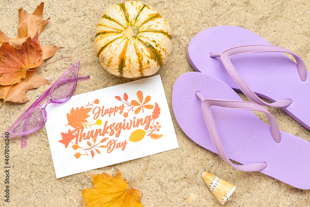 干树叶、太阳镜、南瓜、人字拖和纸卡片，上面写着沙子上的感恩节快乐