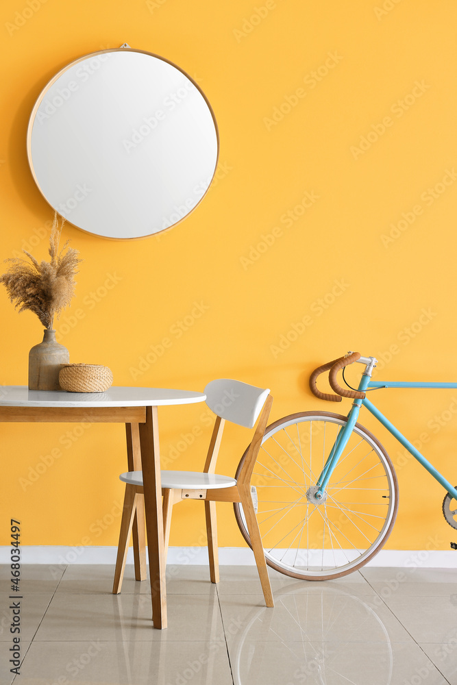 黄色墙壁附近有花瓶和自行车的餐桌