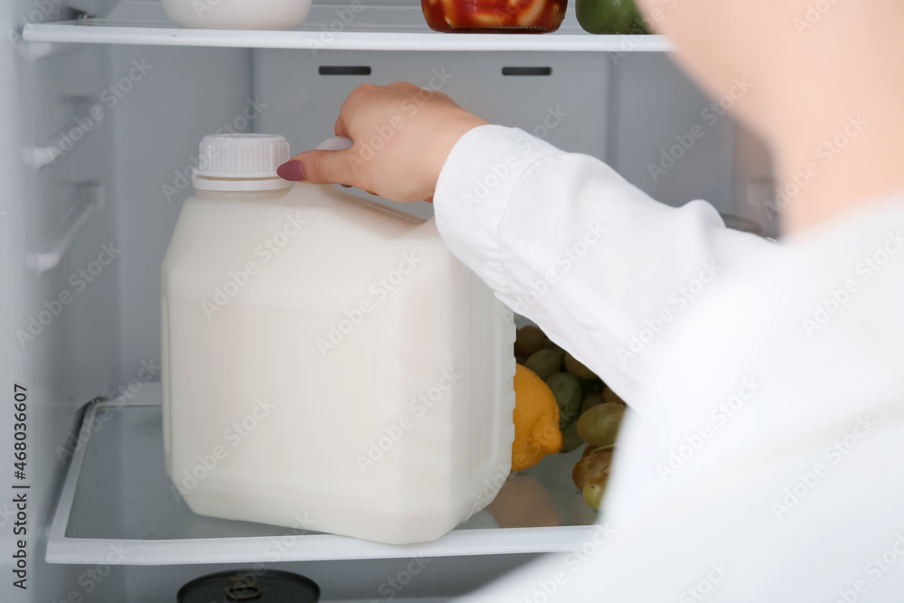 Woman taking gallon bottle of milk from refrigerator