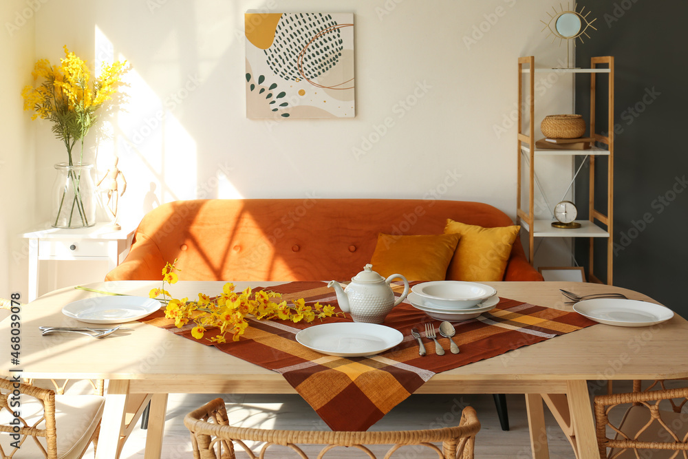 浅色餐厅中的木制餐桌，配有盘子和鲜花