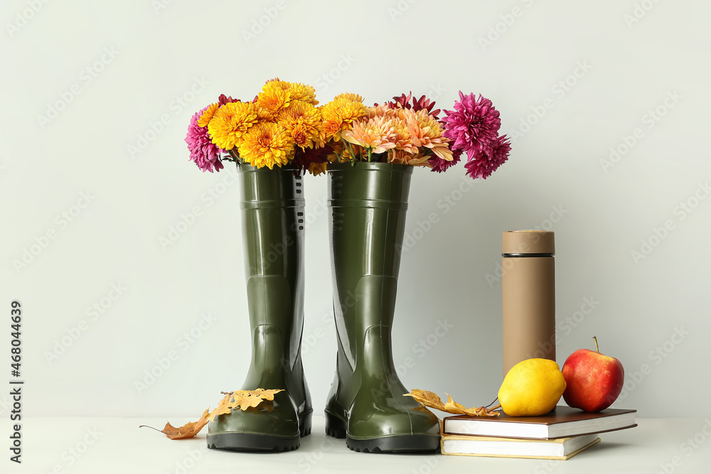 白底带花、保温瓶、书籍和水果的橡胶靴
