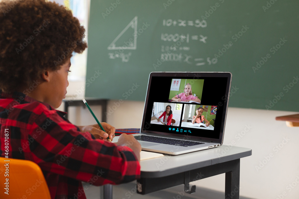 非裔美国男孩使用笔记本电脑进行视频通话，屏幕上有不同的小学生