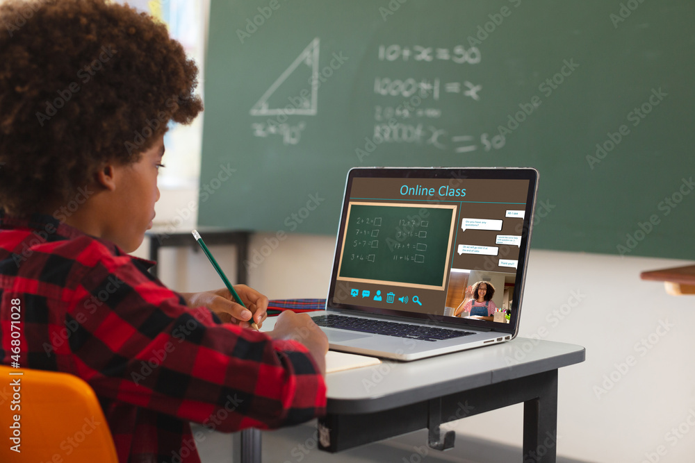 非裔美国男孩用笔记本电脑视频通话，屏幕上有女老师