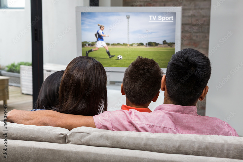 一家人坐在家里一起看电视上的足球比赛的后视图
