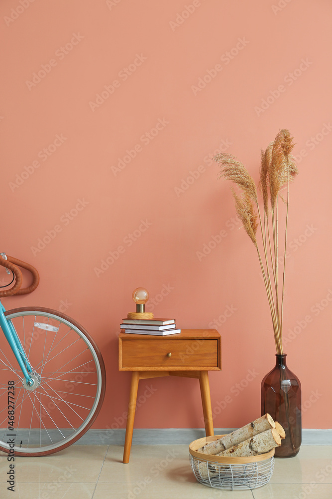 粉红色墙壁附近有灯、书、木柴、花瓶和自行车的桌子