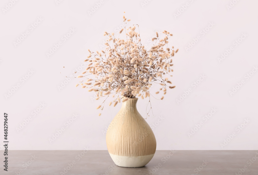 光墙附近桌子上有漂亮的干小穗的花瓶