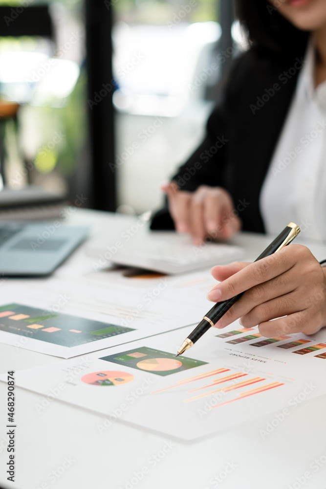 商人用图表报告笔指着营业额，用笔记本电脑分析数据