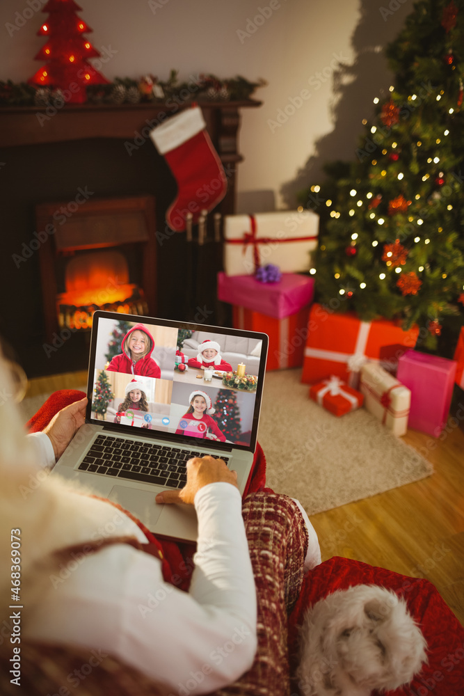 圣诞老人与四个微笑的高加索女孩进行笔记本电脑圣诞集体视频通话