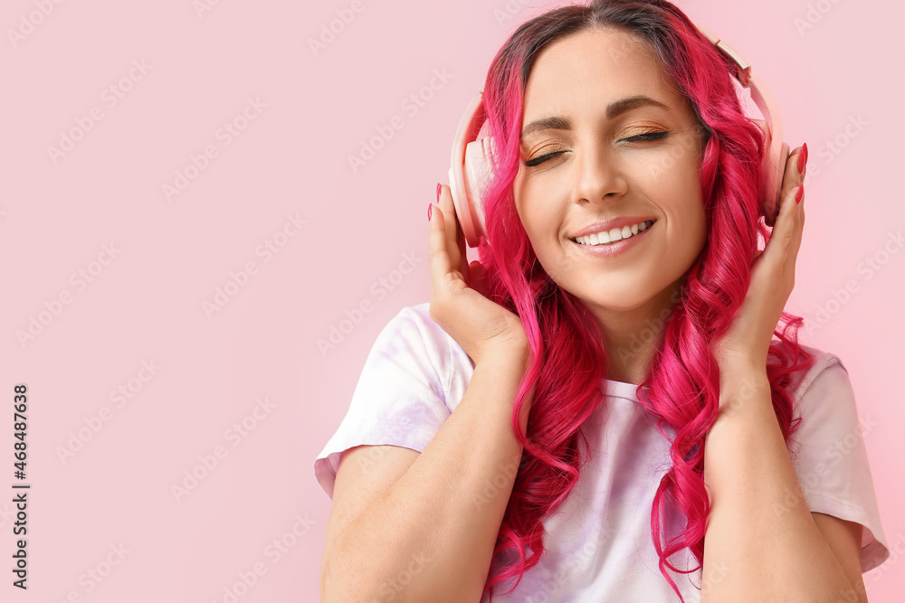 美丽的女人，有着不同寻常的明亮头发，在彩色背景下听音乐