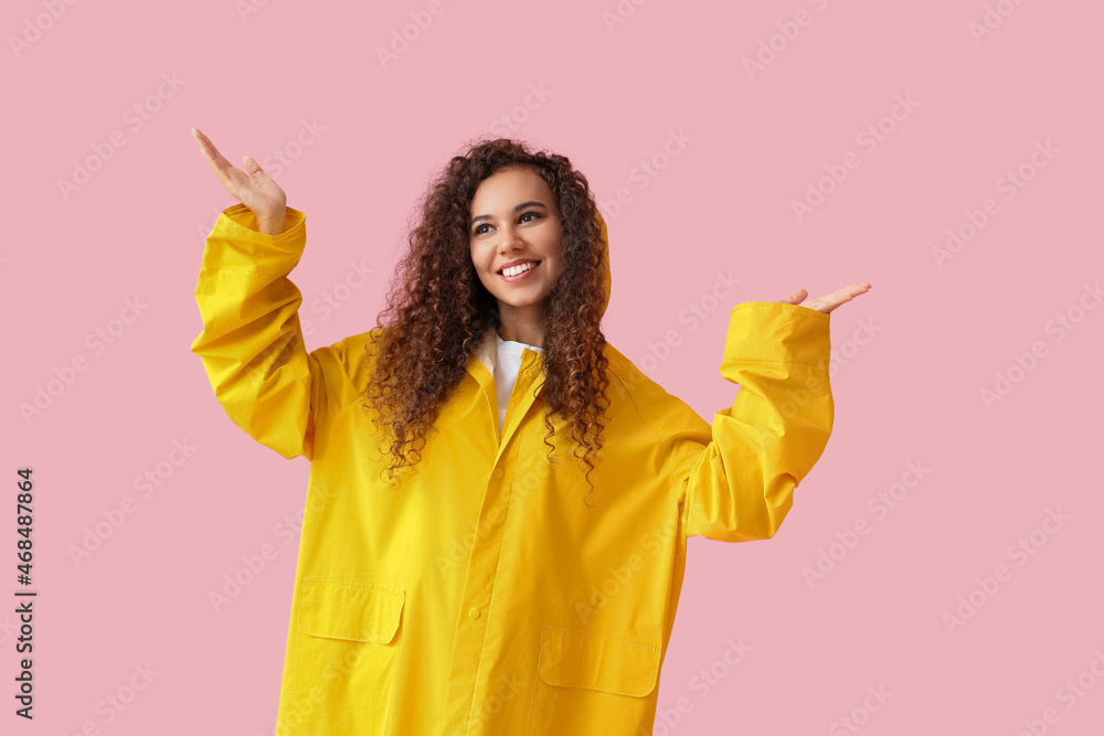 身穿粉色背景黄色雨衣的年轻非裔美国妇女