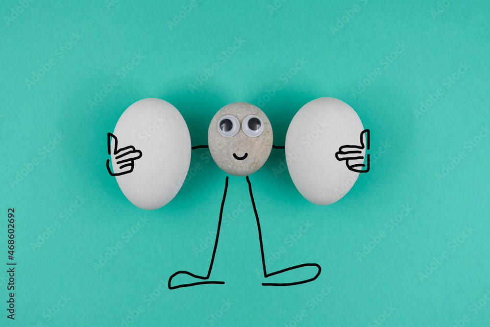 可爱的鹅卵石脸上挂着两个干净的白色鸡蛋，背景是蓝色的纸