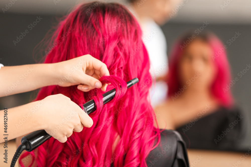 发型师在美容院为年轻女性做头发
